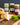 Different jars of Zia Pia pesto and spread on a wooden board with cheese and basil