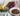 Platter with cheese, grapes, crackers, nuts, and a bowl of eggplant caponata on a wooden surface.