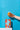 Hand holding a glass of orange juice with a box of oranges against a blue background