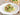 Plate of green pasta with broccoli and bacon on a wooden table