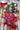 Three colorful tea packages with fruit illustrations on a wooden surface with red cups and fruits.