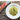 Spaghetti dish with zucchini on a white plate next to a package of spaghetti.
