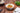 White bowl of oragnic fusilli with sauce on a brown table surrounded by ingredients