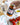 Hand holding a jar of Zia Pia tomato pesto with a bottle of olive oil and tomatoes in the background.
