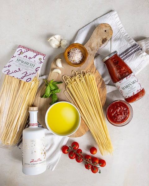 Zia Pia organic pasta, extra virgin olive oil and tomato sauce on a light surface.