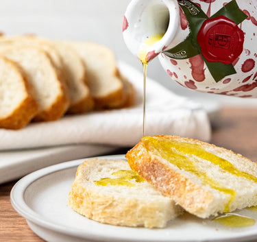 Extra Virgin Olive Oil in Ceramic being poured over sourdough bread.