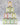 Tins of various flavors of olive oils stacked in a pyramid on a white counter with a gray background
