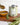 Tin of rosemary flavored olive oil on a wooden board with rosemary sprigs and a oil being poured into a bowl
