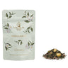 Tea package with floral design and loose tea leaves on a white background