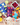 Three colorful tea bags with fruit and a mesh bag on a wooden surface