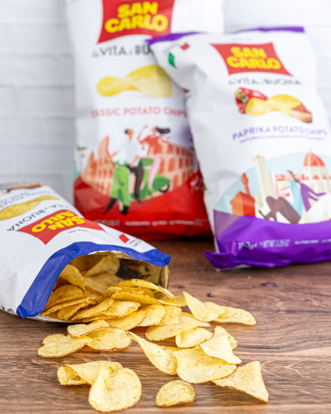 San Carlo potato chip bags on a wooden surface with one bag open showing chips.