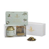 A gift box set of La Via del Té Marguerite loose leaf tea, including a jar and a gold stainless steel tea infuser, with a floral design on the packaging.